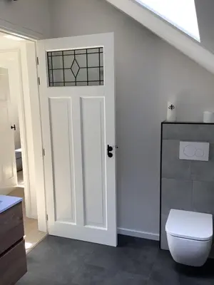 a bathroom with a white door and a toilet at Vakantiewoningeikenhof in Londerzeel