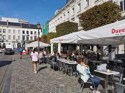 a group of people sitting at tables on a city street at Design europarlament apartment with private terrace in Brussels