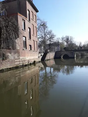 a building next to a river next to a bridge at Het Maelslot (Mechelen) in Mechelen