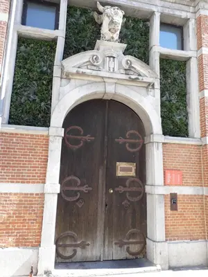 a wooden door in a brick building with a statue above it at Het Maelslot (Mechelen) in Mechelen