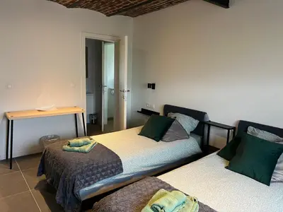 a bedroom with two beds and a table in it at Les Cerisettes in Wavre
