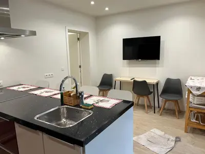 a kitchen with a sink and a living room with chairs at Les Cerisettes in Wavre