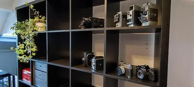 a black book shelf with two cameras on it at Fitness loft 50 m2 in Zemst