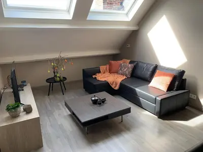 a living room with a black leather couch and a table at De Kempische Akker in Westerlo