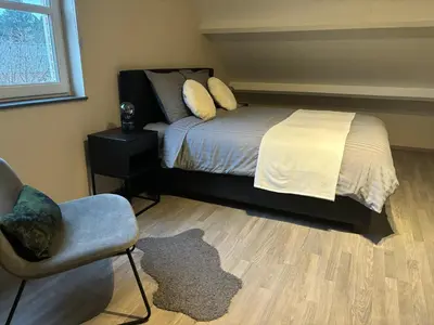 a bedroom with a bed and a chair and a window at De Kempische Akker in Westerlo