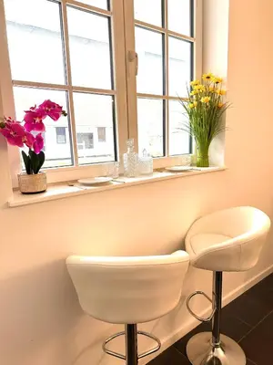 a room with a white chair and flowers in a window at Royal Horses in Overijse