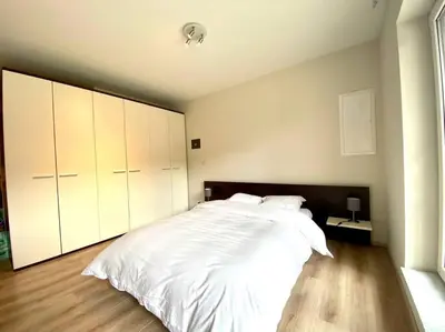 a bedroom with a large bed with white sheets at Studio hypercentre Bruxelles in Brussels