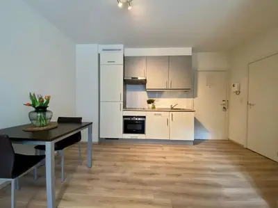 a kitchen with white cabinets and a table with chairs at Studio hypercentre Bruxelles in Brussels