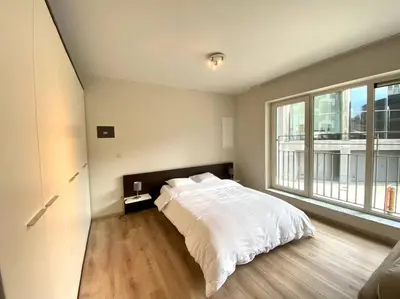 a bedroom with a white bed and a large window at Studio hypercentre Bruxelles in Brussels