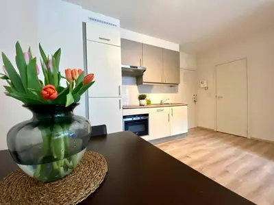 a vase with flowers sitting on a table in a kitchen at Studio hypercentre Bruxelles in Brussels