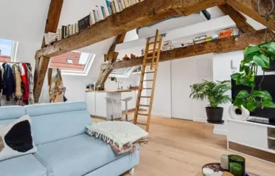 a living room with a blue couch and a ladder at Beautiful cosy apartments in the heart of Antwerp in Antwerp