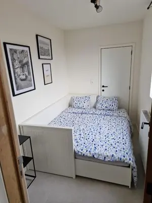 a white bedroom with a bed with blue pillows at Phoenix in Ghent