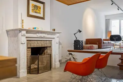 a living room with a fireplace and orange chairs at Ramón Studio in Antwerp