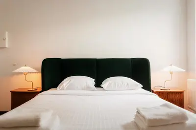 a bedroom with a large bed with white sheets and two lamps at Unbeatable Location Explore Ghent on Foot! in Ghent