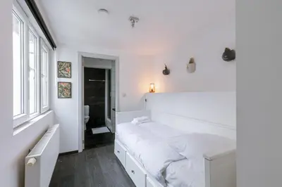 a white bedroom with a large bed and a window at Unbeatable Location Explore Ghent on Foot! in Ghent