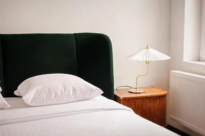 a bed with a green headboard and a lamp on a table at Unbeatable Location Explore Ghent on Foot! in Ghent