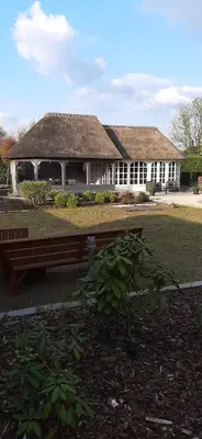 a building with a grass roof with a bench in front at Kamer 22 Bed & Breakfast in Poppel