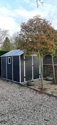 a blue garage with a tree in front of it at Kamer 22 Bed & Breakfast in Poppel