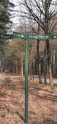 a green street sign in the middle of a park at Kamer 22 Bed & Breakfast in Poppel