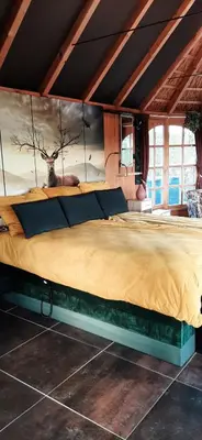 a bedroom with a large bed with a deer painting on the wall at Kamer 22 Bed & Breakfast in Poppel