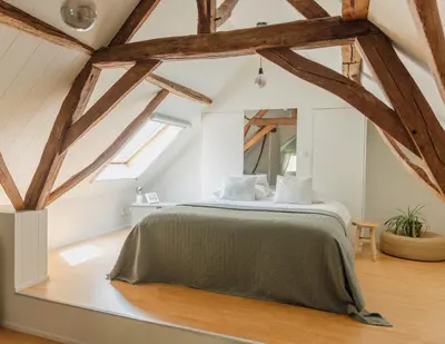 a bedroom with a large bed in a room with wooden beams at Bijgebouw hoeve in landelijke omgeving in Putte