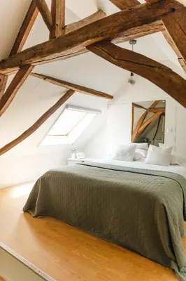 a bedroom with a large bed with wooden beams at Bijgebouw hoeve in landelijke omgeving in Putte