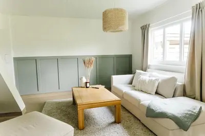 a living room with a white couch and a table at Bijgebouw hoeve in landelijke omgeving in Putte