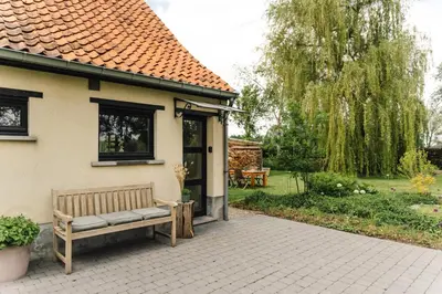 a wooden bench sitting outside of a house at Bijgebouw hoeve in landelijke omgeving in Putte